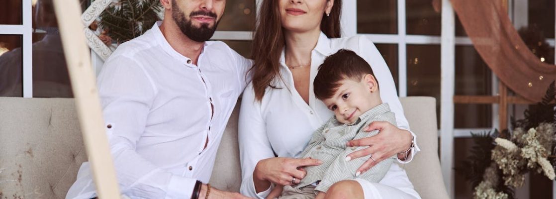 A loving family sits together indoors, capturing a heartwarming moment with parents and child.